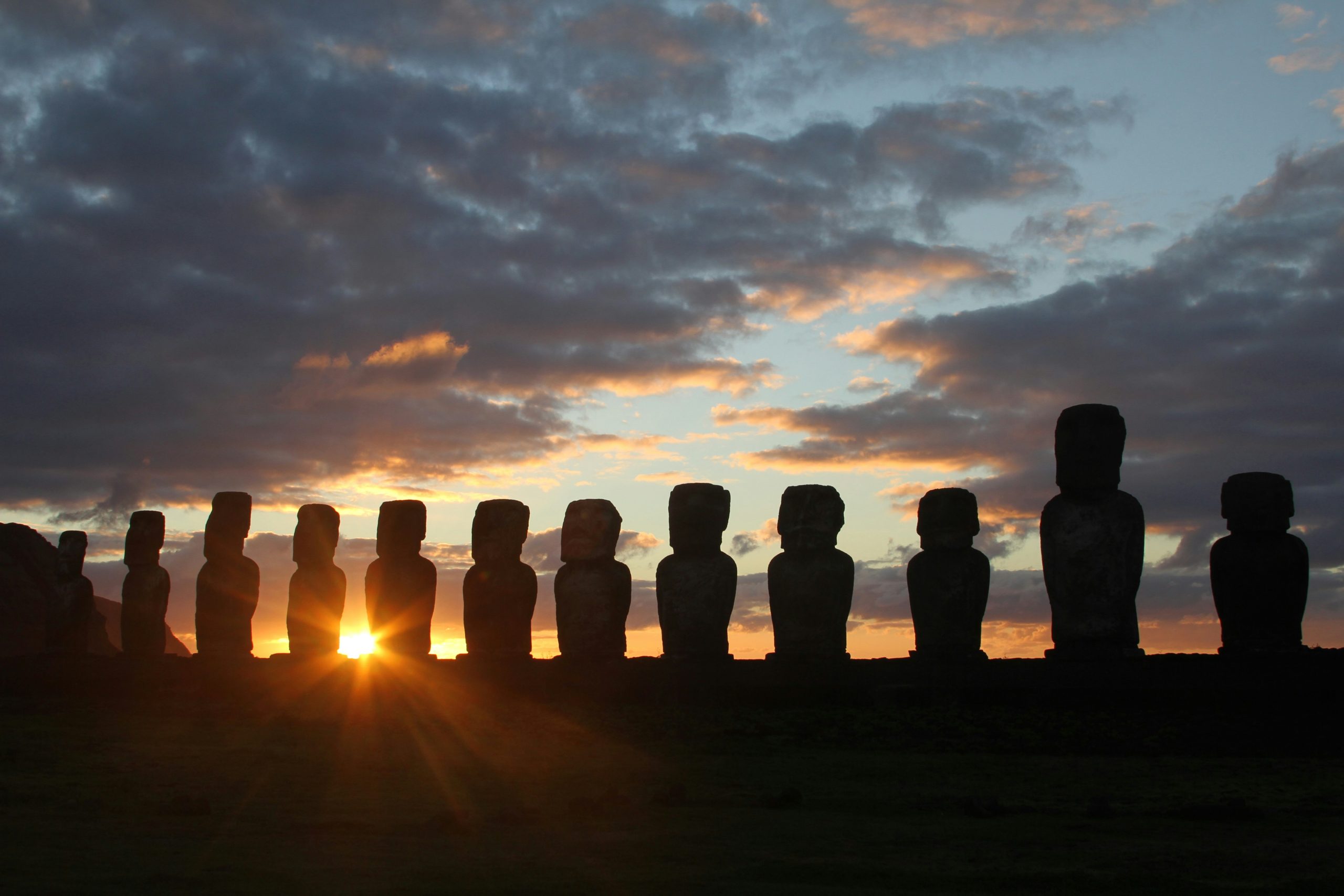 Sun rises or sets behind Moai statues