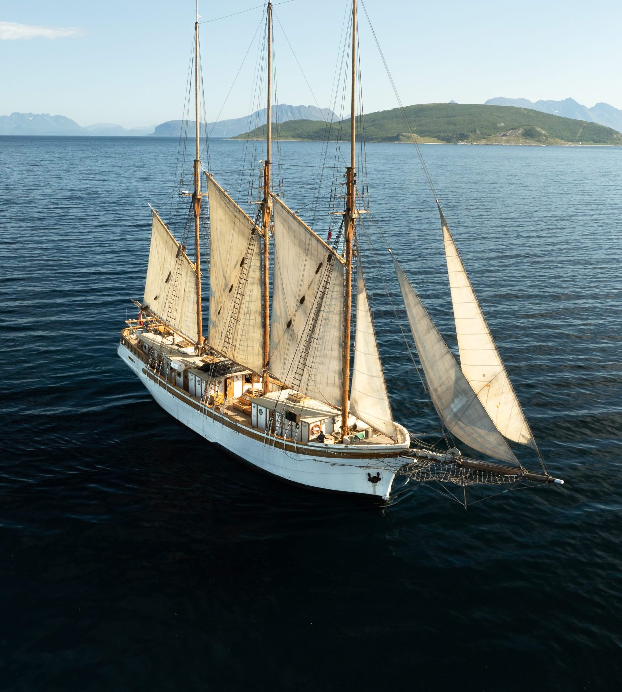 A small white ship in full sail