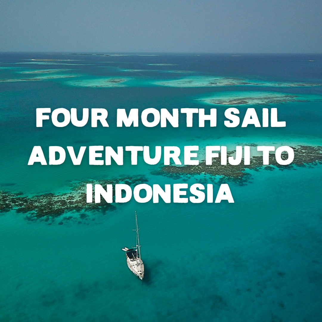 A drone shot of a small white sailing vessel with vast blue and turquoise sea